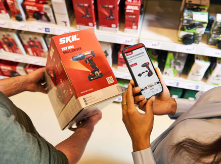 Webinar: Praktisch gebruik GS1 Data Source webinterface in de doe-het-zelf-, tuin- en diersector - GS1 Graded DHZT Man En Vrouw Scannen QR Code Op Product In Bouwmarkt PRESENTATIE