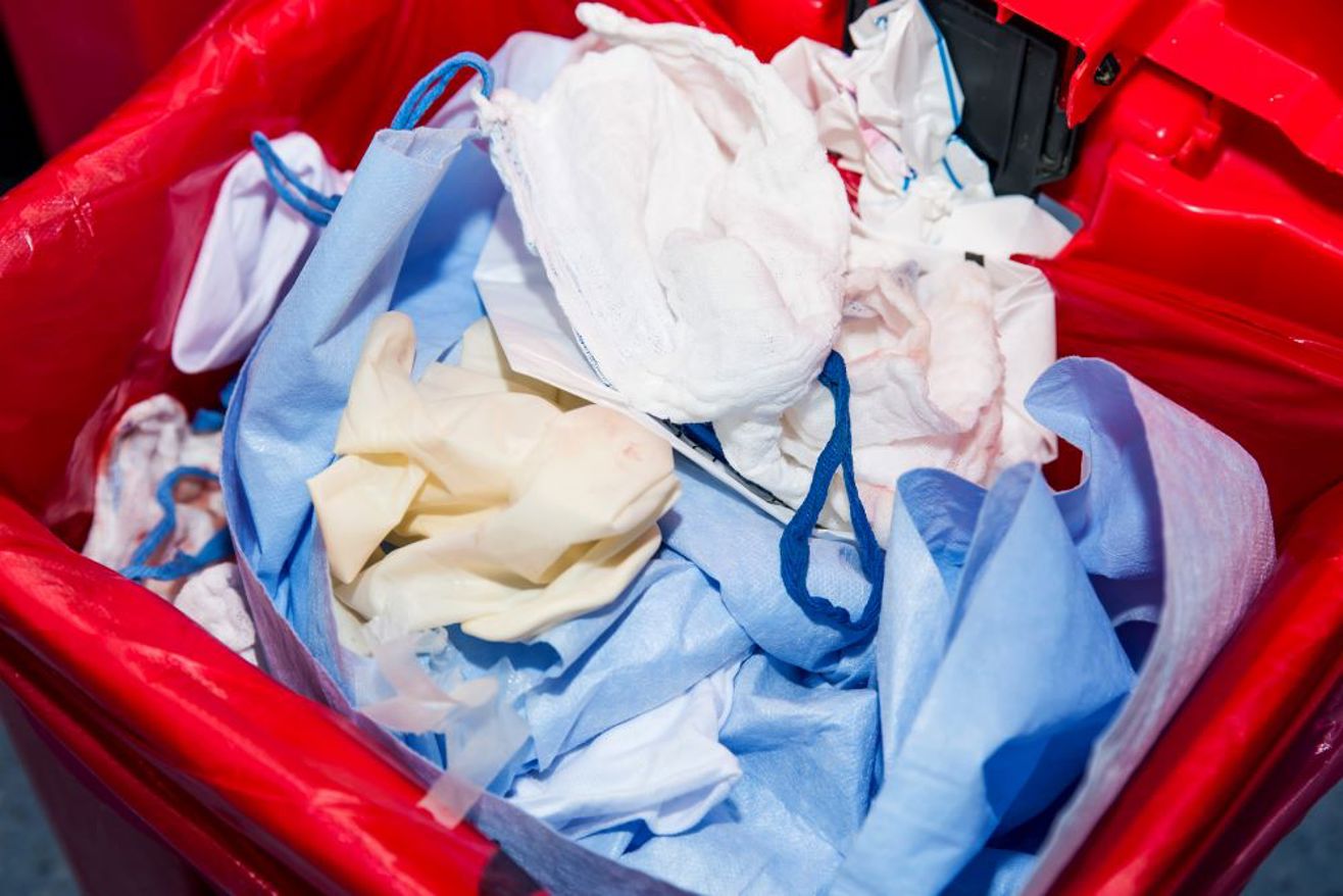 Duurzaamheid in de gezondheidszorg - Rode Afvalbak Met Wegwerp Kledij En Mondkapjes (1)